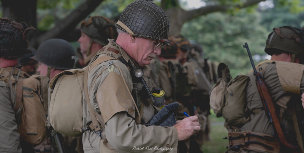 An army officer inspecting his troops, walking confidently among the ranks. His posture is authoritative, and he observes the soldiers closely, reflecting leadership and the importance of maintaining discipline and readiness within the unit.